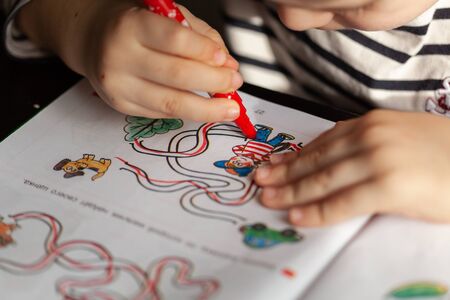Small boy at home drawing lines in book hometask