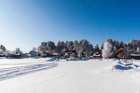 Snowy field with traces, trees at winter, frosen lakeの写真素材