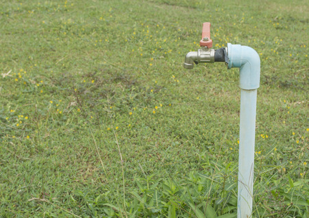 water faucet with green grass backgroundの写真素材