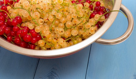 fresh red and white currants on a blue board closeup