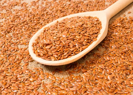 flaxseed on canvas background with a wooden spoonの写真素材