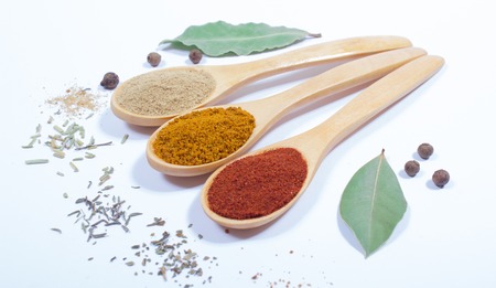 Spice powder isolated on white background. Paprika, curry and ginger on a wooden spoon.の写真素材