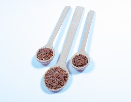 flaxseed on white background with a wooden spoonの写真素材
