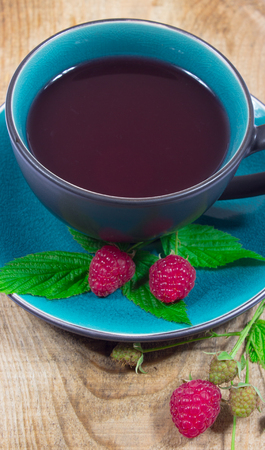 Tea raspberry on a wooden background with fresh raspberries.