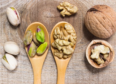 Closeup of a walnut and pistachios on wooden background.の写真素材