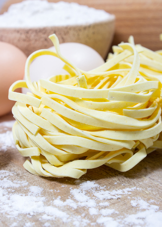 Raw homemade pasta and ingredients for pasta on wooden background.の写真素材