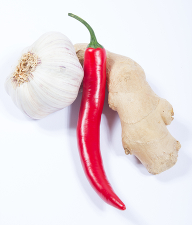 Closeup of a chili pepper, garlic and ginger on a white background.の写真素材