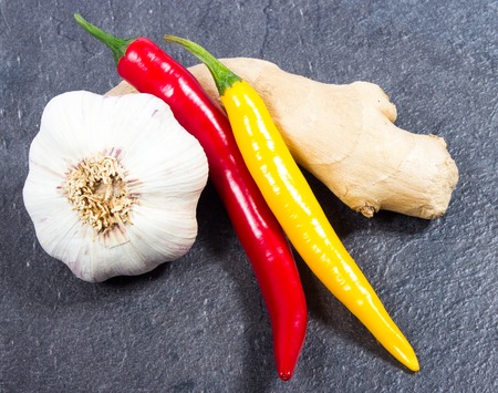 Closeup of a chili pepper, garlic and ginger on a black background.の写真素材