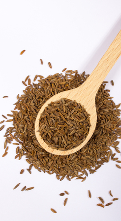 Ground cumin in a spoon, isolated on white background.