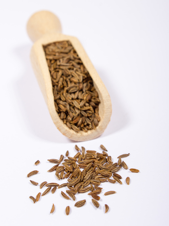 Ground cumin in a spoon, isolated on white background.