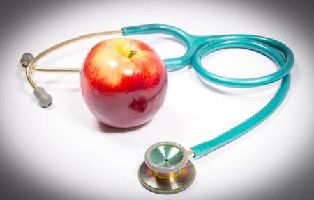 Closeup of fresh apple with stethoscope isolated on white background.の写真素材