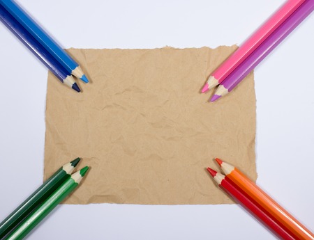 Colorful pencil crayons on the paper background, closeup.