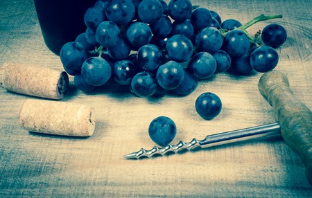 Close up - glass of red wine with a sprig of grapes on a wooden background.の写真素材