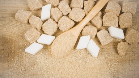 Cubes of sugar - brown sugar cane on the wooden background.の写真素材