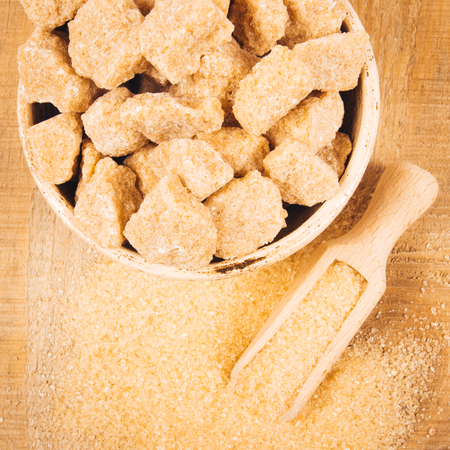 Cubes of sugar - brown sugar cane on the wooden background.の写真素材