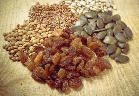 Flaxseed, pumpkin, raisins, lentils and sunflower seeds in wooden spoons. Seeds - a concept of healthy food additives.の写真素材