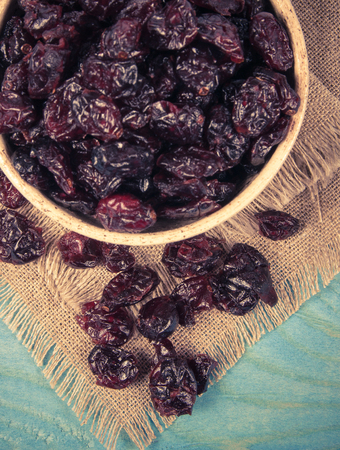 Dried raw cranberries fruit in bowl on the wooden background.の写真素材