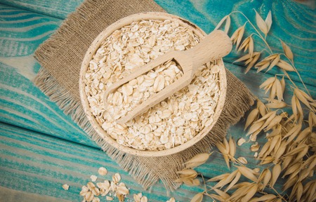 Oat and oatmeal on the wooden background. Healthy eating concept.