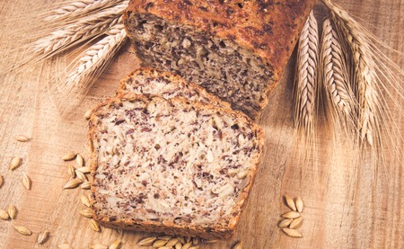 Multi-grain bread on a wooden background. The source of fiber, complex carbohydrates, B vitamins and...
