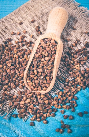 Buckwheat in a ceramic bowl on wooden table. Conception of healthy eating.
