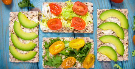 Snack from wholegrain rye crispbread cracker with cherry tomatoes, avocado and salad. Conception of...