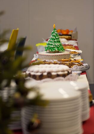 Simple cake dekorated with an eatable christmas tree pops out amonst other pies and cakes on a christmas party.の写真素材