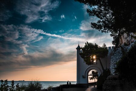 Entrance of the Miramare Castle in Trieste Italy in Europe next to the mediterranean sea with a couple while sunset. Dramatic view of the sky. The couple stands out as a silhouette.の写真素材