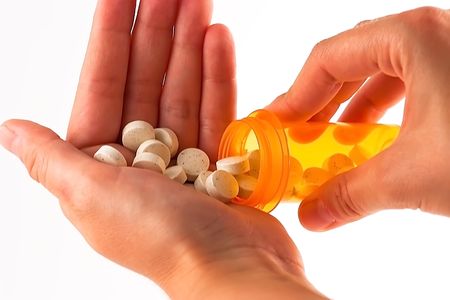 Pills poured from a bottle onto hand - close up - isolated on white backgroundの写真素材