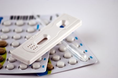 Pregnancy test and birth control pills isolated on a white background
