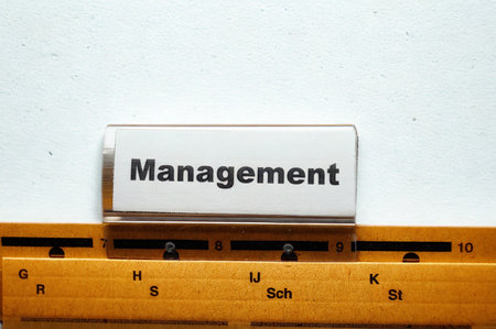 A white card with the word Management printed in black text sits on a wooden ruler with markings and letters.の写真素材