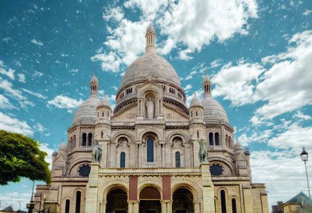 The iconic SacrÃ©-CÅur Basilica in Paris stands grandly against a vibrant blue sky dotted with fluffy white clouds.の写真素材