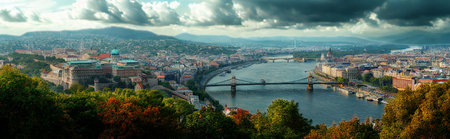 A sweeping aerial view captures a European city nestled beside a wide river, with rolling mountains in the distance under a dramatic, cloudy sky.の写真素材