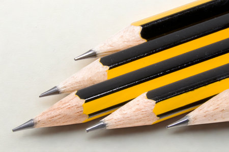 A close-up view of several sharpened yellow and black pencils arranged in a diagonal line, showcasing their pointed tips and wooden bodies.の写真素材