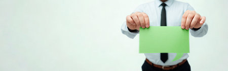 A person in a white shirt and black tie holds a bright green envelope in front of them against a plain white background.の写真素材