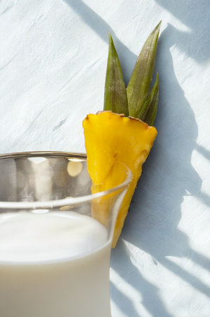 A close-up of a cool, creamy beverage in a glass, adorned with a vibrant slice of pineapple and its green leaves.の写真素材