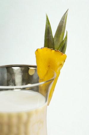 A close-up shot of a tropical cocktail with a bright yellow pineapple wedge and green leaf garnish...