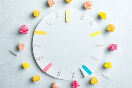 A white clock face is decorated with colorful sticky notes, arranged like numbers on a clock.の写真素材