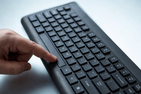 A finger presses a key on a black computer keyboard, highlighting the act of typing or inputting data.の写真素材