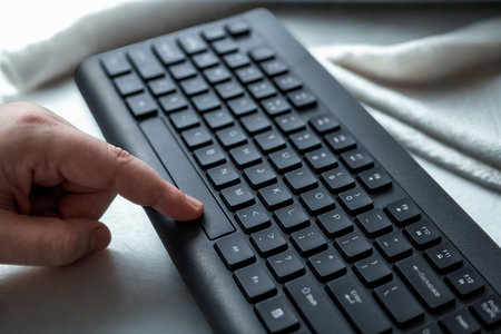 A close-up shot shows a person's finger pressing a key on a black computer keyboard, suggesting typing or interaction.の写真素材