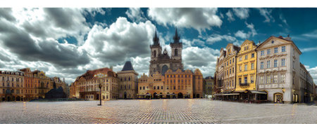 A wide-angle view of a cobblestone square in a European city, featuring ornate buildings and a towering Gothic cathedral under a dynamic sky.の写真素材