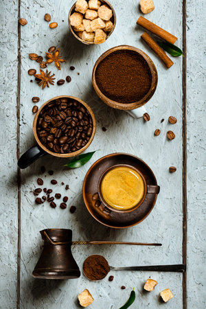 Overhead view of coffee beans, ground coffee, spices, and a cup of coffee on a rustic wooden surface.の写真素材