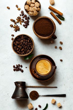Overhead view of coffee beans, grounds, spices, sugar cubes, and brewing equipment arranged artfully on a light surface.の写真素材