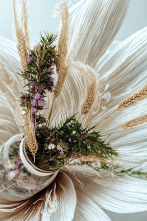 A close-up of a delicate dried flower arrangement featuring delicate petals, greenery, and small purple flowers.の写真素材