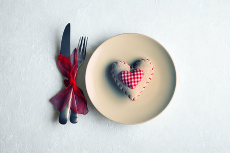 A simple, elegant table setting with a plate, cutlery, and a charming heart decoration, perfect for a romantic occasion.の写真素材
