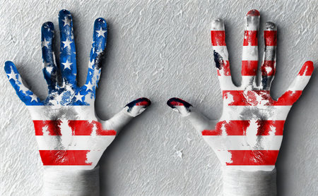 Two hands are painted with the American flag pattern, showcasing stars and stripes against a textured gray surface.の写真素材