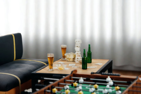 A foosball table sits in the foreground with drinks on a nearby table, suggesting a fun gathering.の写真素材