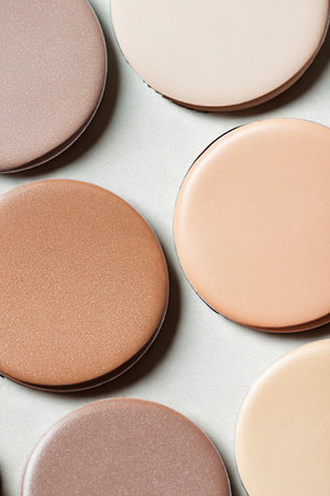 A collection of circular makeup pans displaying a range of skin tones and blush shades, showcasing texture and color.の写真素材
