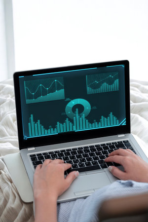 A person's hands are actively typing on a laptop keyboard. The screen displays a detailed digital...