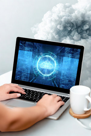Hands typing on a laptop displaying a glowing cloud icon and digital network on screen, with a mug nearby.の写真素材