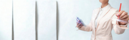 A professional woman in a light-colored suit holds a stylus and a tablet, seemingly interacting with a digital screen or data.の写真素材